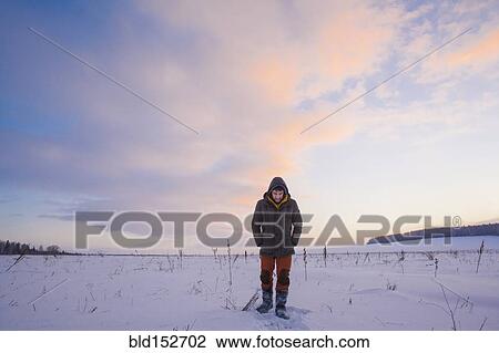 Stock Image - Mixed race man walking in snowy field. Fotosearch