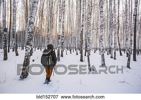 Stock Photo - Mixed race man walking in snowy forest. Fotosearch