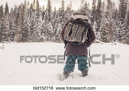 Stock Photograph - Mixed race man walking in snowy forest. Fotosearch