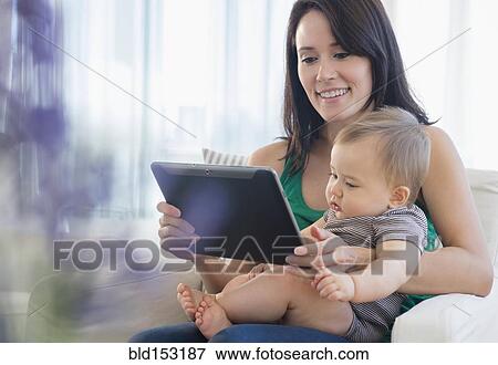 Stock Photo - Mixed race mother and baby using digital tablet. Fotosearch