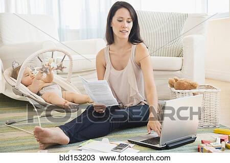 Mixed race mother paying bills on laptop with baby on floor View Large Photo Image Stock Image - Mixed race mother paying bills on laptop with baby on floor. Fotosearch
