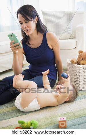 Mixed race mother using cell phone with baby on floor View Large Photo Image Stock Image - Mixed race mother using cell phone with baby on floor. Fotosearch