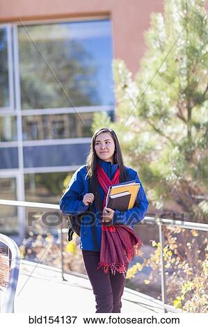 Mixed race student holding books on campus View Large Photo Image Stock Photo - Mixed race student holding books on campus. Fotosearch