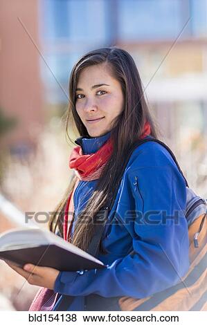 Stock Photo - Mixed race student holding books on campus. Fotosearch