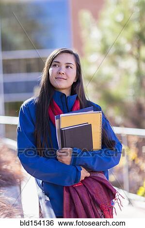 Stock Photograph - Mixed race student holding books on campus. Fotosearch