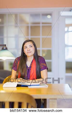 Picture - Mixed race student reading in library. Fotosearch