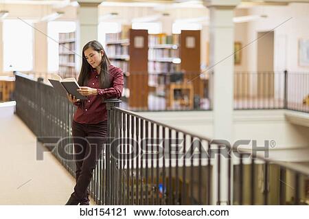 Stock Image - Mixed race student reading in library. Fotosearch