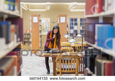 Stock Image - Mixed race student reading in library. Fotosearch