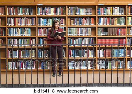 Stock Photo - Mixed race student reading in library. Fotosearch