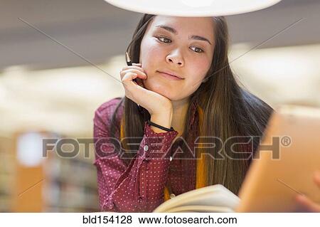 Stock Photo - Mixed race student reading in library. Fotosearch