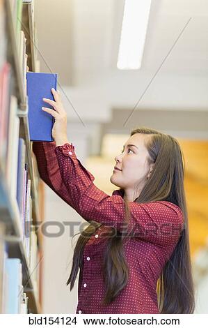 Mixed race student selecting book in library View Large Photo Image Picture - Mixed race student selecting book in library. Fotosearch
