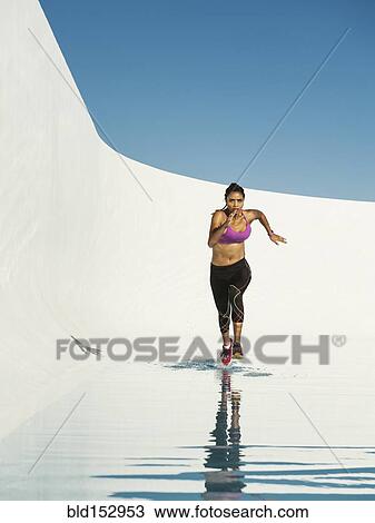Stock Image - Mixed race woman running on water surface. Fotosearch