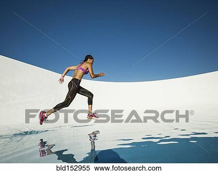 Stock Photography - Mixed race woman running on water surface. Fotosearch