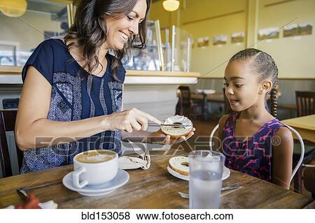 Stock Photo - Mother and daughter eating breakfast in cafe. Fotosearch