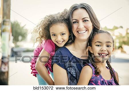 Stock Image - Mother and daughters smiling outdoors. Fotosearch