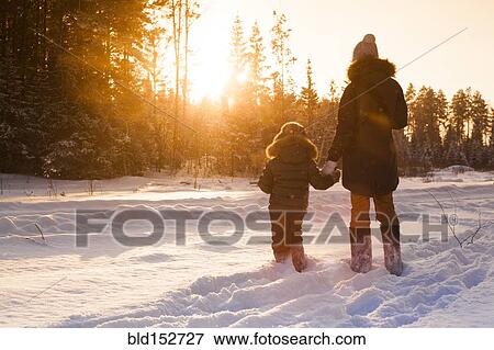 Mother and son walking in snowy forest clearing View Large Photo Image Stock Photo - Mother and son walking in snowy forest clearing. Fotosearch