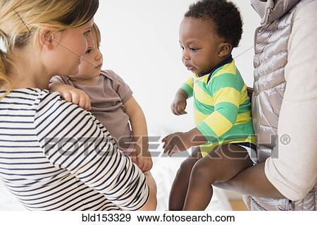Stock Photo - Mothers introducing babies on play date. Fotosearch