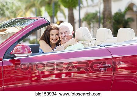 Picture - Older Caucasian couple driving in convertible. Fotosearch