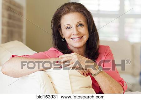 Stock Image - Older Caucasian woman sitting on sofa. Fotosearch