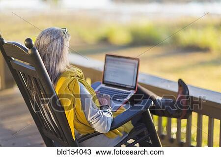 Older Caucasian woman using laptop on porch View Large Photo Image Stock Image - Older Caucasian woman using laptop on porch. Fotosearch