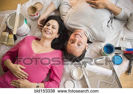 Stock Photo - Overhead view of couple laying on drop cloth during remodeling. Fotosearch