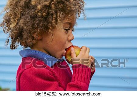 Stock Image - Pacific Islander boy eating apple outdoors. Fotosearch