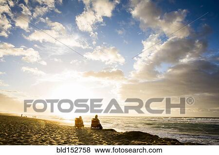 People relaxing on beach at sunrise View Large Photo Image Stock Photo - People relaxing on beach at sunrise. Fotosearch