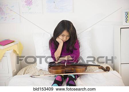 Pouting Vietnamese girl holding violin in bedroom View Large Photo Image Stock Photo - Pouting Vietnamese girl holding violin in bedroom. Fotosearch