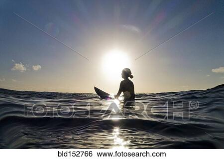 Stock Photograph - Silhouette of surfer sitting on surfboard in ocean. Fotosearch