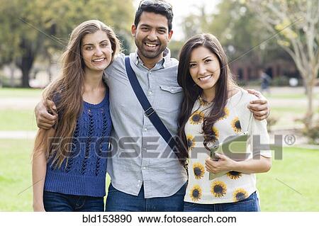 Stock Image - Smiling friends hugging in park. Fotosearch