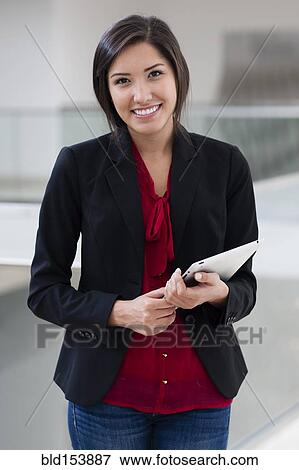 Stock Photo - Smiling Hispanic businesswoman holding digital tablet. Fotosearch