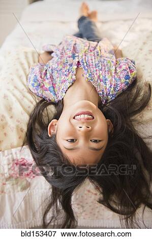 Stock Photo - Smiling Vietnamese girl laying on bed. Fotosearch