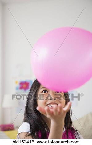 Stock Photograph - Smiling Vietnamese girl playing with pink balloon. Fotosearch