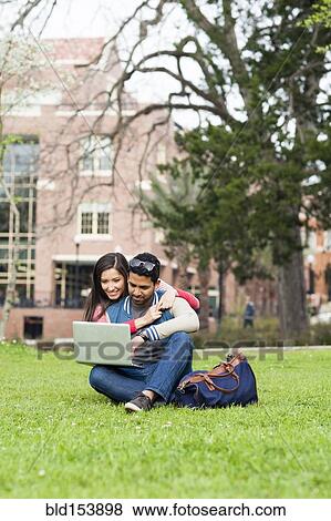 Stock Photo - Students hugging and using laptop on campus. Fotosearch