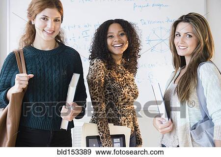 Stock Photo - Students smiling with textbooks and digital tablet in classroom. Fotosearch