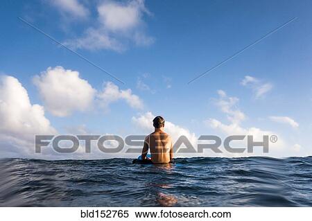 Stock Photography - Surfer sitting on surfboard in ocean. Fotosearch