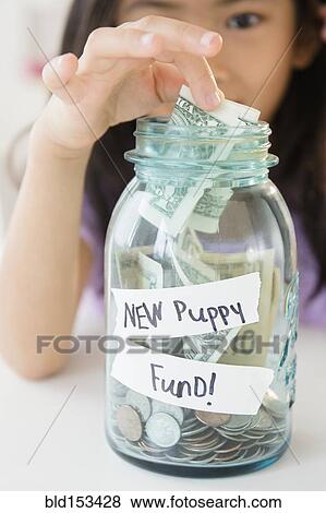 Stock Photo - Vietnamese girl saving money in new puppy fund. Fotosearch