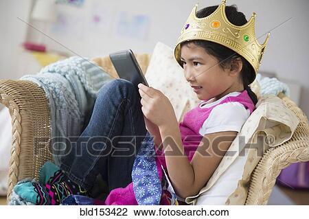 Vietnamese girl with crown using digital tablet in armchair View Large Photo Image Stock Image - Vietnamese girl with crown using digital tablet in armchair. Fotosearch