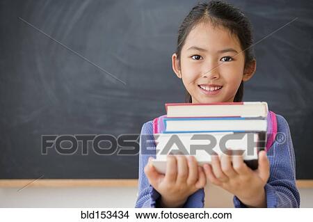 Picture - Vietnamese student carrying textbooks in classroom. Fotosearch