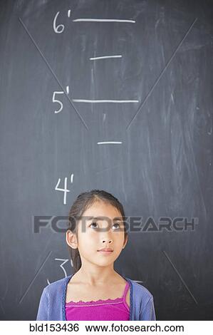 Stock Photograph - Vietnamese student standing under height markers on chalkboard. Fotosearch