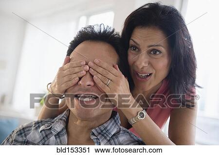 Stock Image - Woman covering eyes of husband. Fotosearch