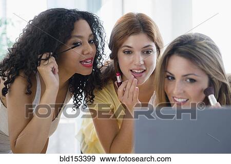Stock Photo - Women applying makeup in mirror. Fotosearch