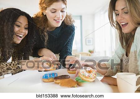 Stock Photo - Women eating donuts at breakfast. Fotosearch