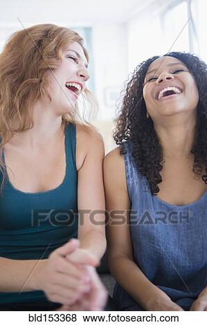 Stock Photo - Women laughing on sofa. Fotosearch
