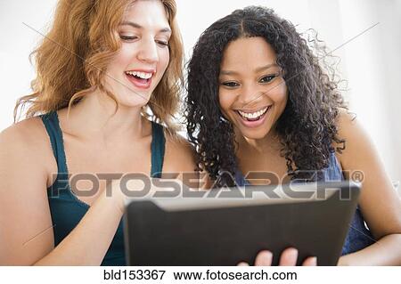 Stock Photo - Women using digital tablet on sofa. Fotosearch