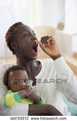 Stock Image - Yawning Black mother holding baby boy. Fotosearch