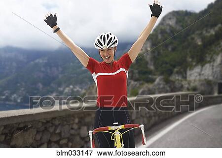 Stock Photo - Caucasian cyclist cheering on remote coastal road. Fotosearch