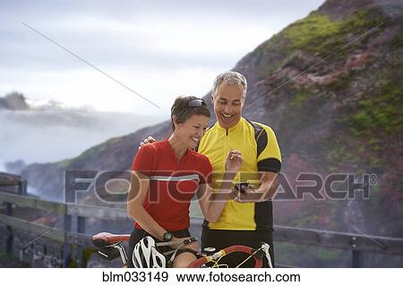 Stock Photo - Caucasian cyclists using cell phone on remote coastal road. Fotosearch