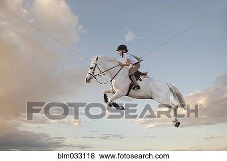 Stock Photo - Caucasian girl riding horse in cloudy sky. Fotosearch