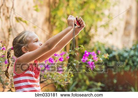 Stock Image - Caucasian girl taking photograph outdoors. Fotosearch